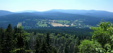 Výhled ze šumavského Stožce na stejnojmennou obec dole (vpravo je vidět nádraží). V pozadí třináctistovkové vrchy Trojmezná, Třístoličník, Plechý a Smrčina.